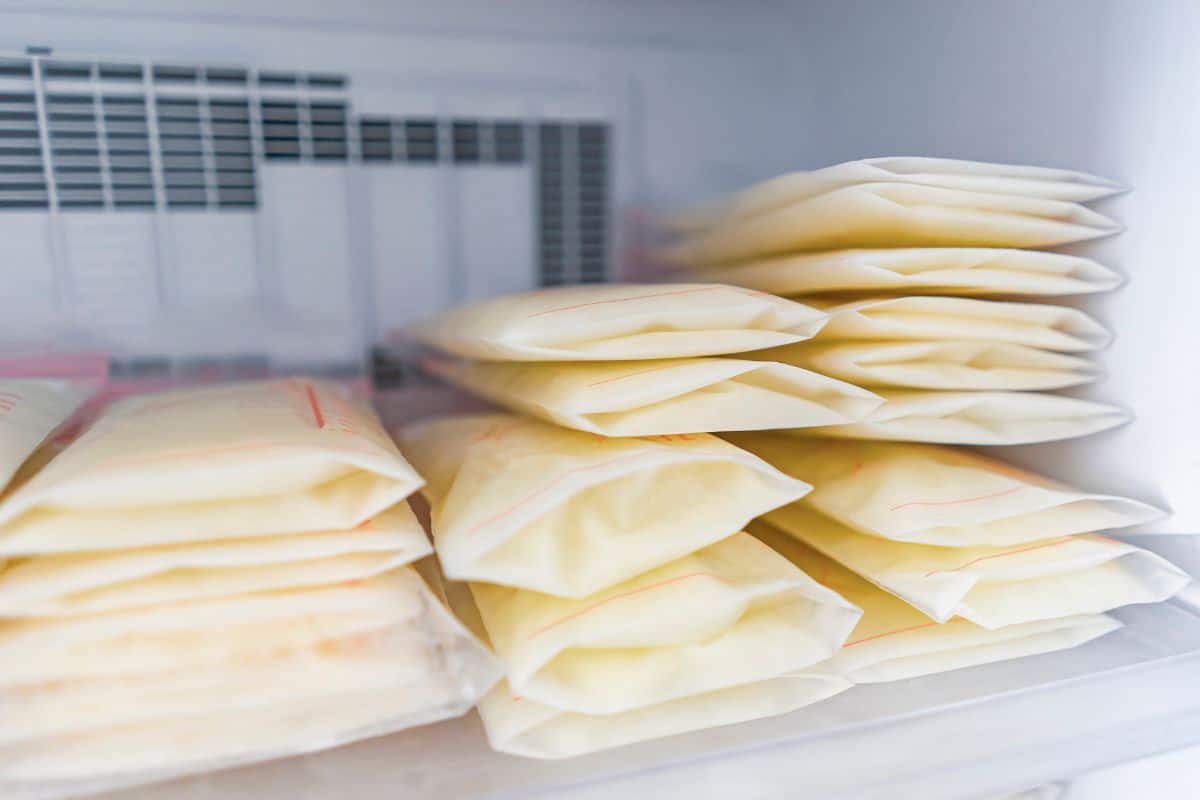 Neatly stacked breast milk storage bags filled with frozen milk inside a freezer. The milk bags are laid flat and organized for efficient storage, following best practices for building a breast milk freezer stash.