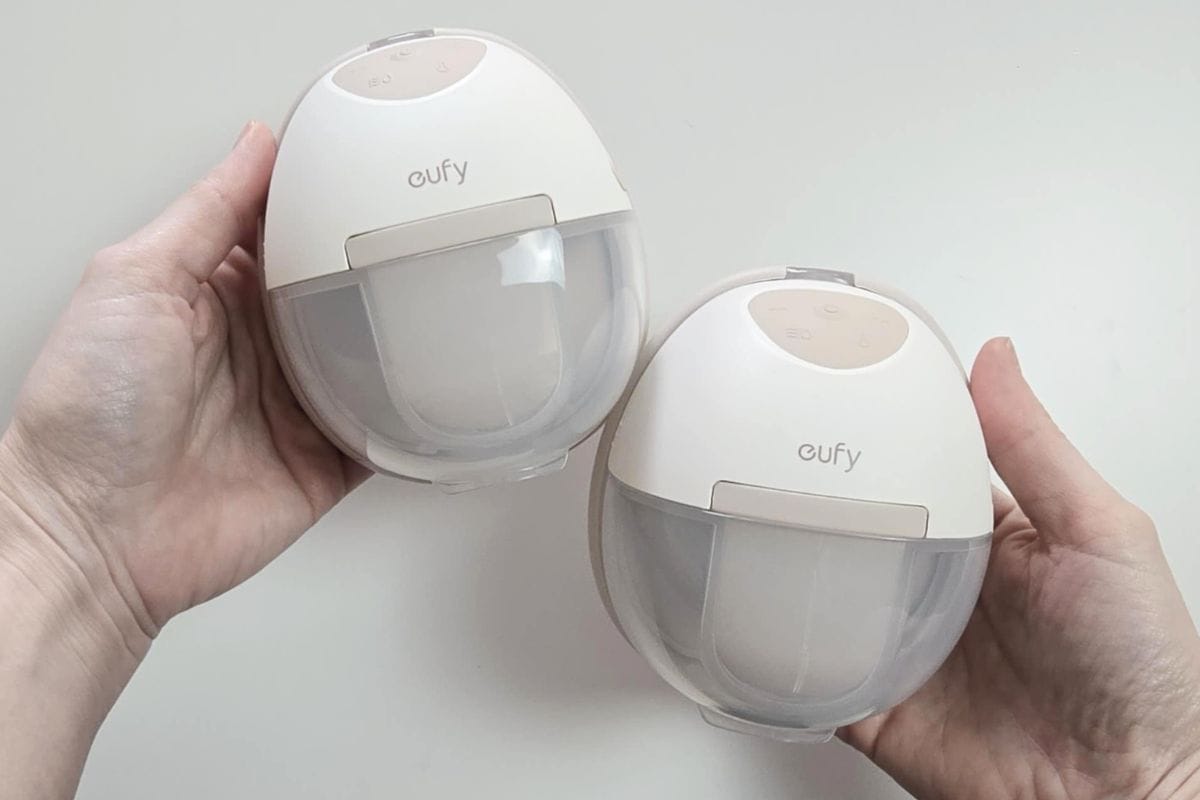Two Eufy E20 wearable breast pumps held in hands, showing compact design and built-in collection cups.