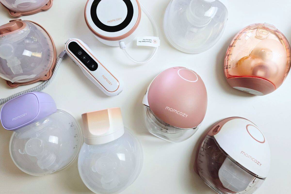 Flat lay of multiple Momcozy wearable breast pumps showing different models, colors, and collection cups arranged on a white background