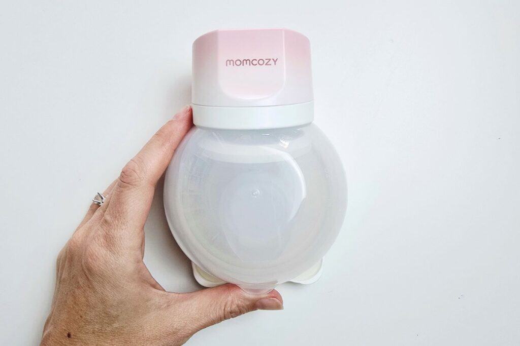 Momcozy S12 Pro Quick wearable breast pump with simplified four part design and large 6oz collection cup shown held in hand.